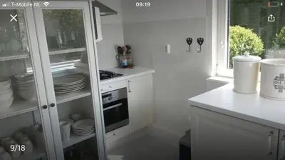 a kitchen with a white cabinet with dishes in it at Vakantiehuis Lara in Warmenhuizen