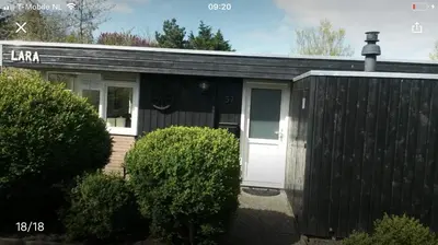 a black and white shed with a white door at Vakantiehuis Lara in Warmenhuizen