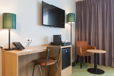 a hotel room with a desk with a television and chairs at Best Western Plus Amstelveen - Amsterdam in Amstelveen