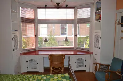 a kitchen with a window with a counter and two chairs at B&B Limes Oudwijk in Utrecht