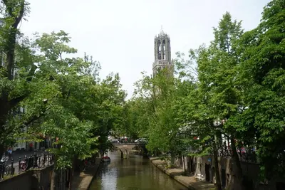 a river with a clock tower in the distance at B&B Limes Oudwijk in Utrecht