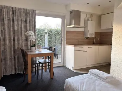a kitchen and dining room with a table and a kitchen and a bed at VISSERSLUST Rooms, Apartments and Houseboats in Vinkeveen