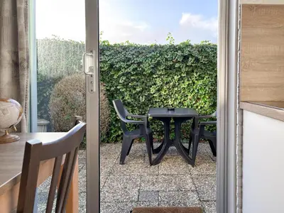 a patio with a table and chairs in front of a hedge at VISSERSLUST Rooms, Apartments and Houseboats in Vinkeveen