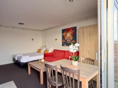a room with a bed and a table with a red couch at VISSERSLUST Rooms, Apartments and Houseboats in Vinkeveen