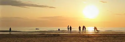 a group of people standing on the beach at sunset at Zeelui in Egmond aan Zee