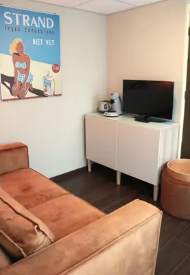 a living room with a couch and a flat screen tv at Zeelui in Egmond aan Zee