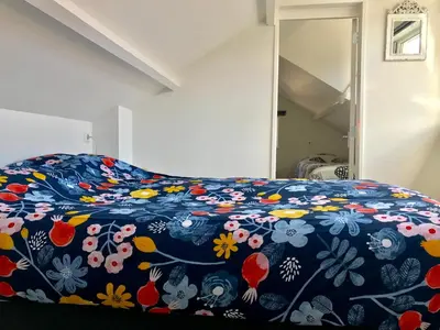 a bed with a blue blanket with flowers on it at Ferienhaus Glücklich am Meer 3 mit Wellnesszugang in Egmond aan Zee
