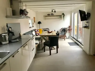 a kitchen and living room with a table and a couch at Ferienhaus Glücklich am Meer 3 mit Wellnesszugang in Egmond aan Zee