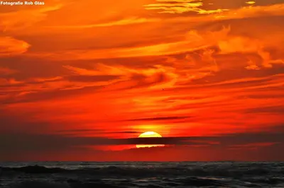 a sunset over the ocean with the sun setting at Ferienhaus Glücklich am Meer 3 mit Wellnesszugang in Egmond aan Zee
