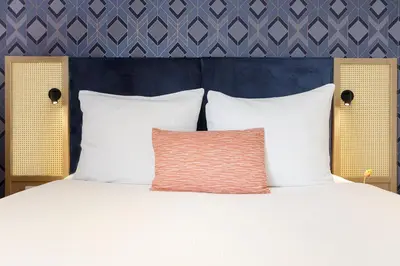 a bed with white pillows and a blue wall at Boutique Apartments Amsterdam in Amsterdam