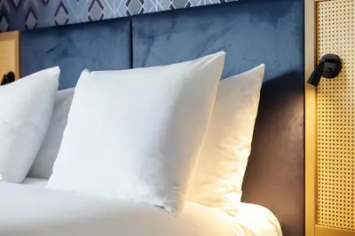 a bed with white pillows and a blue wall at Boutique Apartments Amsterdam in Amsterdam