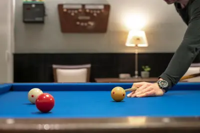 a man playing pool with three balls on a pool table at Hotel Royal in Noordwijk