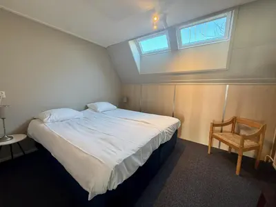 a bedroom with a bed with a window and a chair at Hotel Royal in Noordwijk