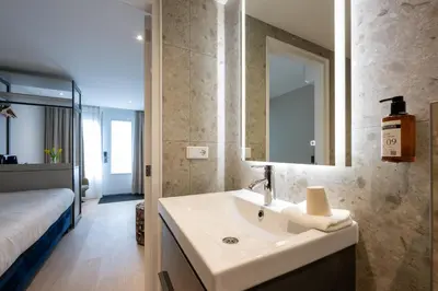 a bathroom with a sink and a mirror and a bed at Hotel Royal in Noordwijk