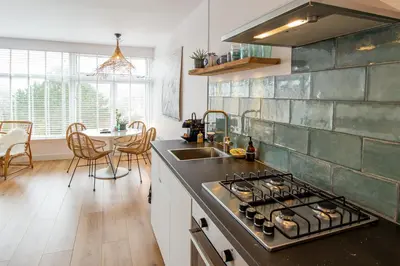 a kitchen with a stove top oven next to a sink at Appartement Zuyd in Zandvoort