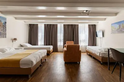 a hotel room with three beds and a chair at Hotel Residence Le Coin in Amsterdam
