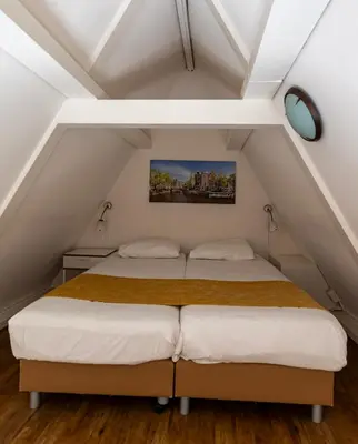 two beds in a attic bedroom with white ceilings at Hotel Residence Le Coin in Amsterdam