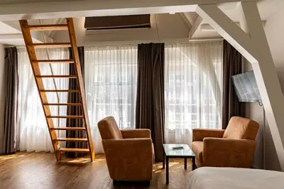 a room with a ladder and two chairs and a bed at Hotel Residence Le Coin in Amsterdam