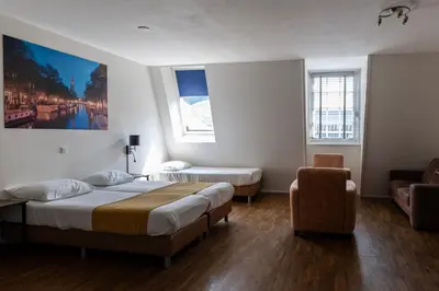 a hotel room with two beds and a chair at Hotel Residence Le Coin in Amsterdam