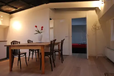 a dining room table with chairs and a vase with flowers at Nachtwacht Apartment in Amsterdam