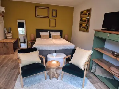 a bedroom with a bed with two chairs and a table at Amsterdam Beach House in Zandvoort