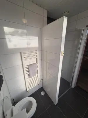 a white bathroom with a toilet and a shower at Amsterdam Beach House in Zandvoort