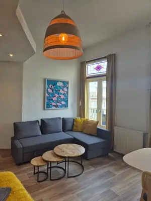 a living room with a blue couch and a table at Amsterdam Beach House in Zandvoort
