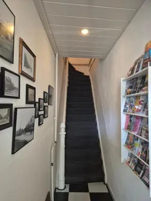 a hallway with a staircase with pictures on the walls at Amsterdam Beach House in Zandvoort