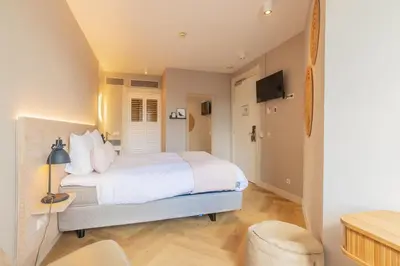 a bedroom with a white bed and a television at City Hotel Rembrandt in Leiden