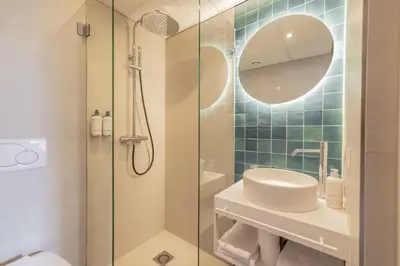 a bathroom with a shower and a sink and a mirror at City Hotel Rembrandt in Leiden