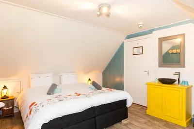a bedroom with a large bed and a yellow dresser at Bed and Breakfast De Pepersteeg in Marken