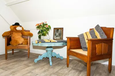a teddy bear sitting on a chair next to a table at Bed and Breakfast De Pepersteeg in Marken
