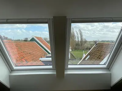 two windows in a room with two roofs at Bed and Breakfast De Pepersteeg in Marken