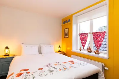 a bedroom with a bed and a window at Bed and Breakfast De Pepersteeg in Marken