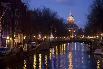 a river with a bridge and a building with a clock tower at studio Vincent van Gogh in Amsterdam