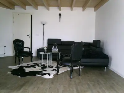 a living room with a black couch and chairs at BedStay41 in Oudewater