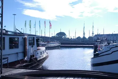 two boats are docked in a river with flags at Passengership Avanti in Amsterdam