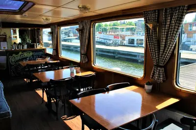 a restaurant with wooden tables and chairs and windows at Passengership Avanti in Amsterdam