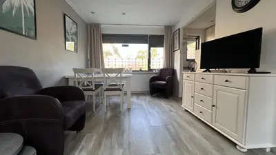 a living room with a television and a table with chairs at Beach-house27 in Egmond aan Zee