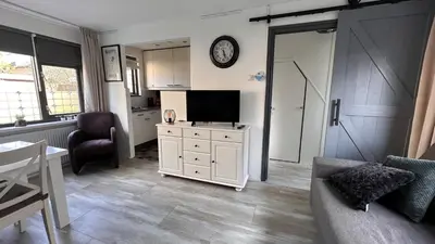 a living room with a couch and a tv on a cabinet at Beach-house27 in Egmond aan Zee