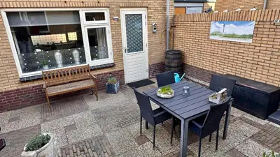 a patio with a table and chairs and a bench at Beach-house27 in Egmond aan Zee