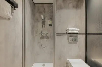a bathroom with a shower and a toilet and a sink at Leonardo Hotel Amsterdam Leidse Square in Amsterdam