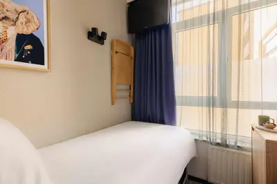 a small bedroom with a bed and a window at Leonardo Hotel Amsterdam Leidse Square in Amsterdam
