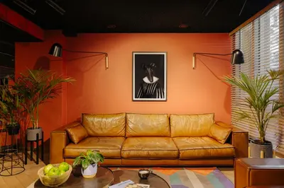 a living room with a brown leather couch at Leonardo Hotel Amsterdam Leidse Square in Amsterdam