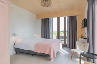 a bedroom with a bed and a large window at De Groene Bollenschuur in Hillegom