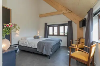 a bedroom with a bed and a table and a chair at De Groene Bollenschuur in Hillegom