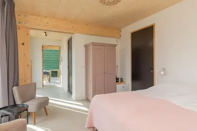 a bedroom with a white bed and a chair at De Groene Bollenschuur in Hillegom