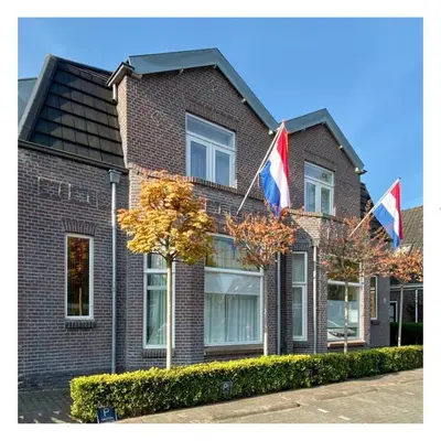two flags flying in front of a brick house at Kranenbergh Boutique Apartments in Bergen