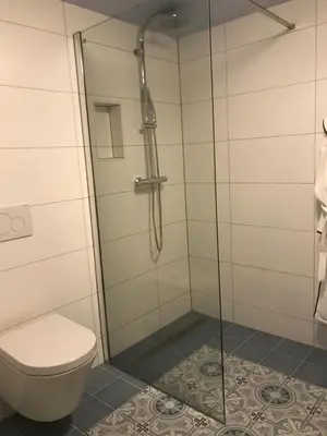 a bathroom with a toilet and a glass shower at Nabij de Molen in Wijdenes