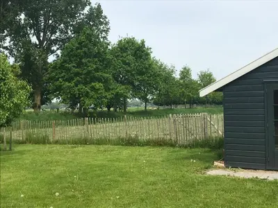 a yard with a wooden fence and a shed at Nabij de Molen in Wijdenes